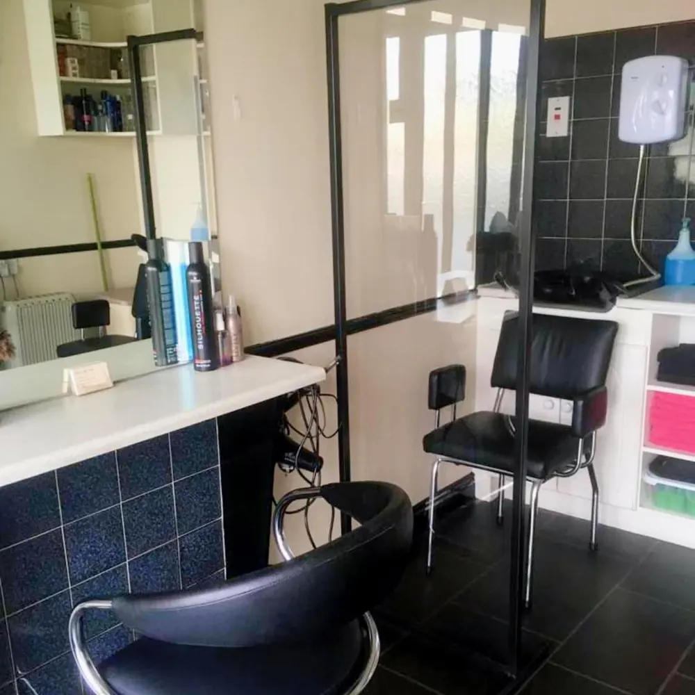 Protective glass screen fitted between styling stations in a hair salon